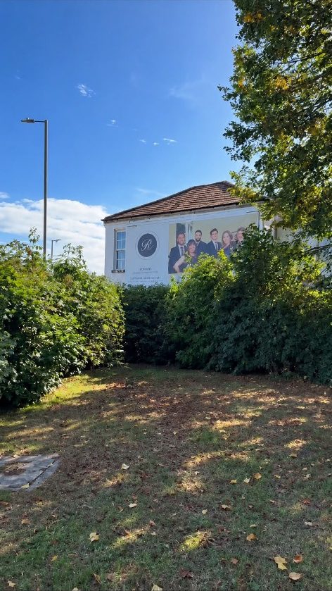 The same hedge cut down in front of the billboard