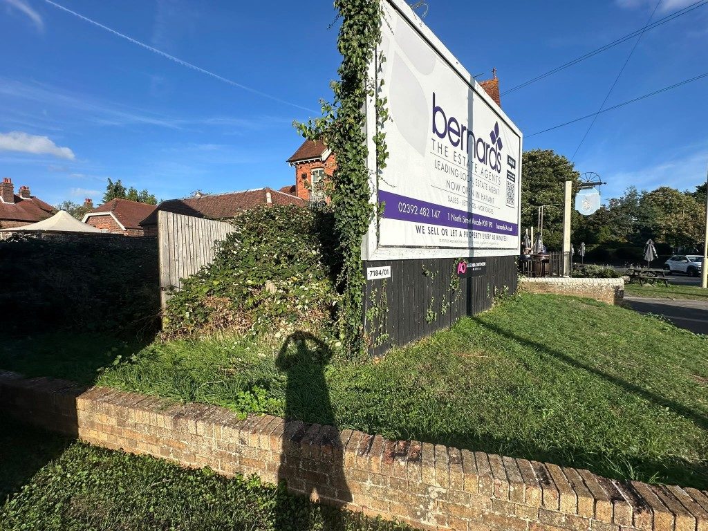 Overgrown ivy and a tangled bed at a commercial frontage in Havant before cutting