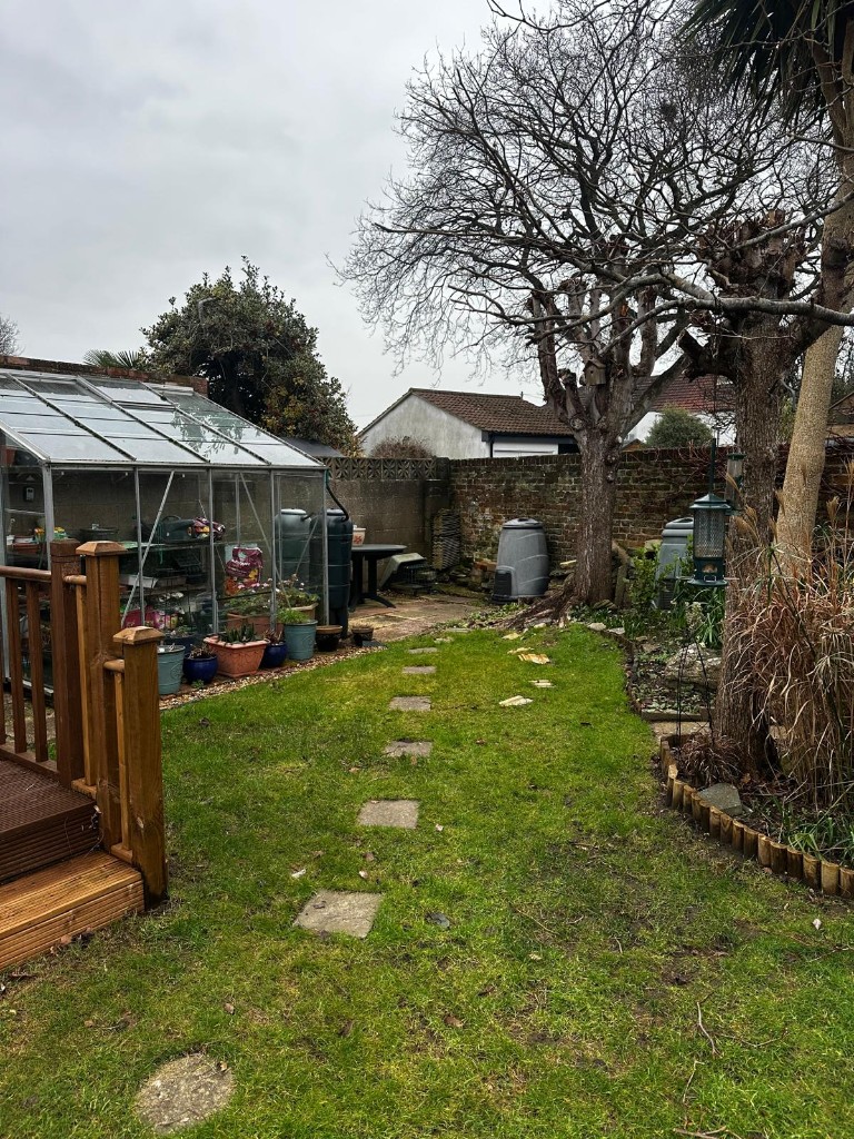 Tired lawn and broken stepping stones beside a greenhouse before a new patio was laid
